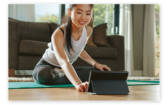 person on yoga mat with tablet