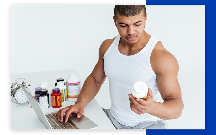 man on laptop looking at vitamin bottles