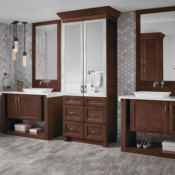 A spacious bathroom with two dark wood vanities and a tall central cabinet with mirrors and drawers. A spacious bathroom with two dark wood vanities and a tall central cabinet with mirrors and drawers.