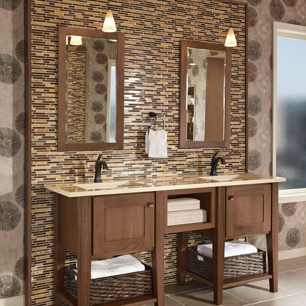A bathroom with a double vanity featuring a wood finish, light countertops, two mirrors, and a textured tile backsplash. A bathroom with a double vanity featuring a wood finish, light countertops, two mirrors, and a textured tile backsplash.