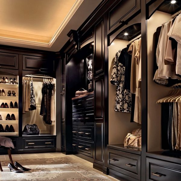 A walk-in closet with dark wood custom cabinetry, built-in shelving, drawers, and hanging rods for clothing and shoes. A walk-in closet with dark wood custom cabinetry, built-in shelving, drawers, and hanging rods for clothing and shoes.