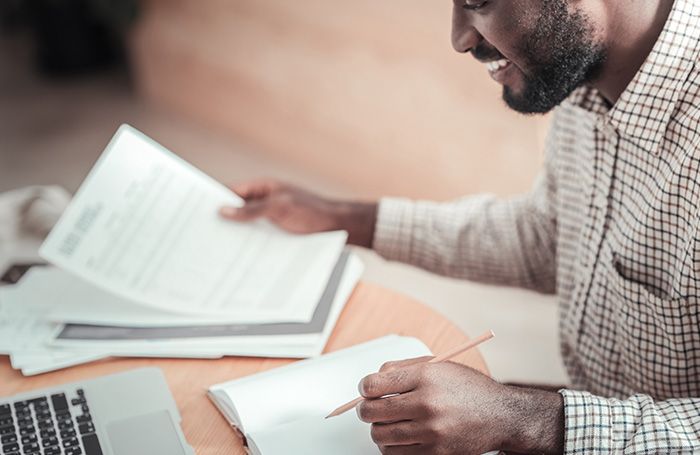 man smiling looking through his papers on laptop