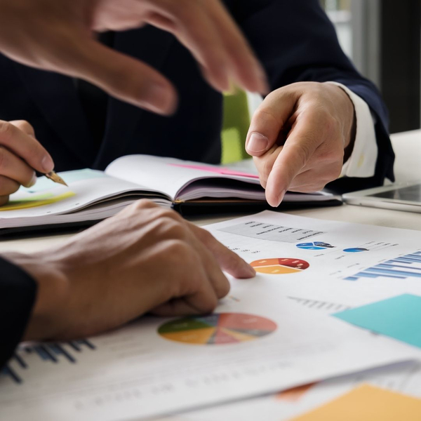 Hands pointing at financial charts and documents, discussing financial data.