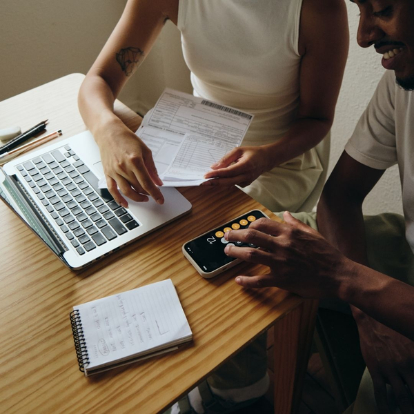 Couple reviewing financial documents and using a calculator, managing personal finances.