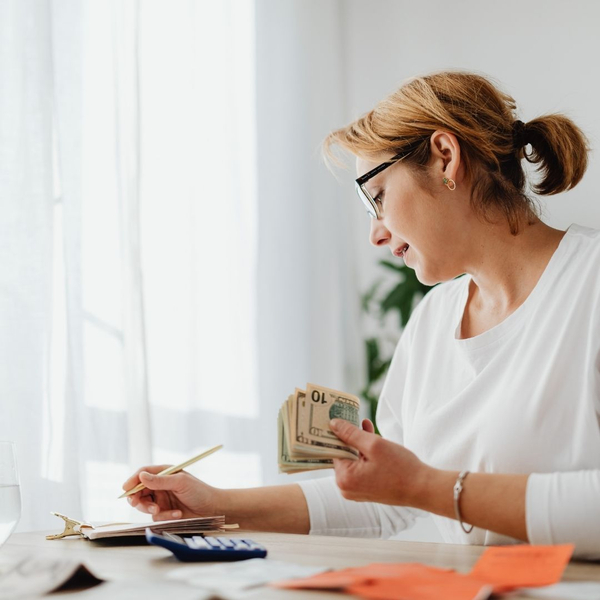 Woman counting money and writing, managing personal finances.