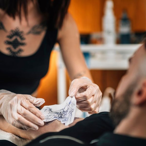 artist applying a tattoo stencil 