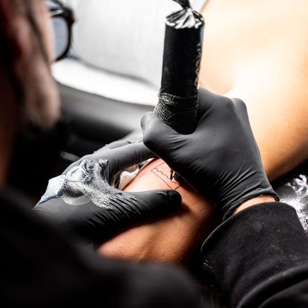 man tattooing arm