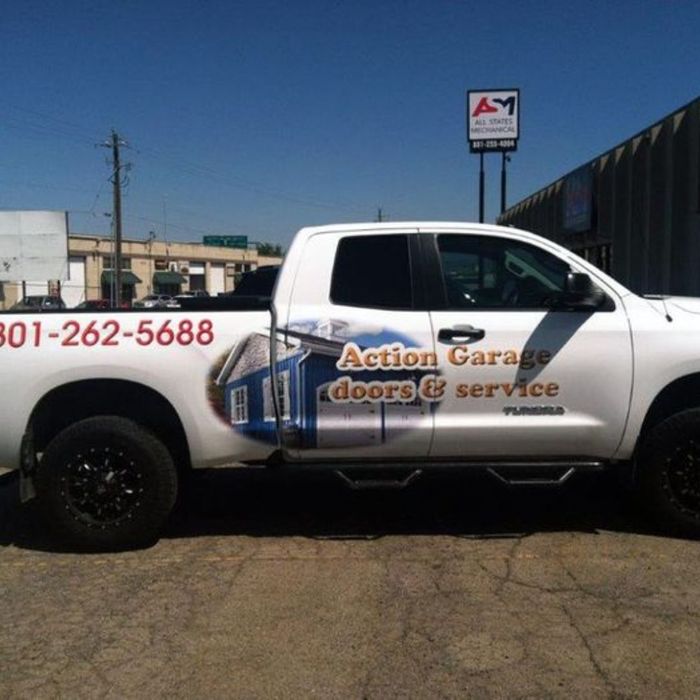White truck with a house graphic and the words ACTION GARAGE doors & Service as a graphic
