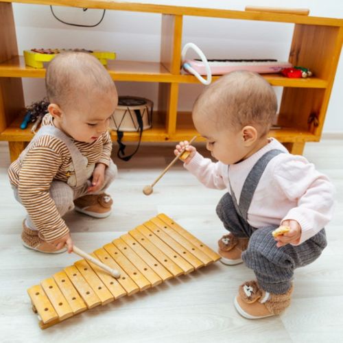 Two children playing on a xylophone together.