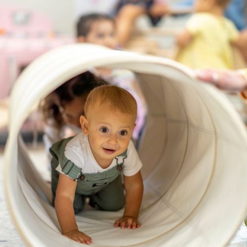 Child crawling through a play tunnel at Sunny Side Academy.