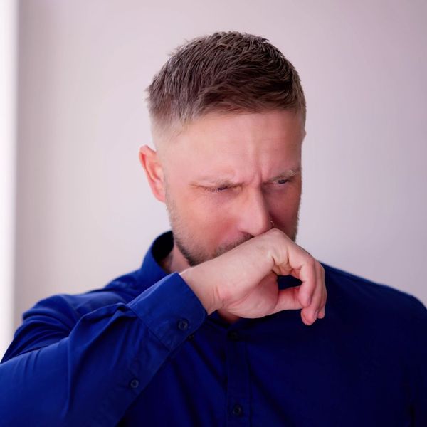 A man grabbing his nose smelling something nasty