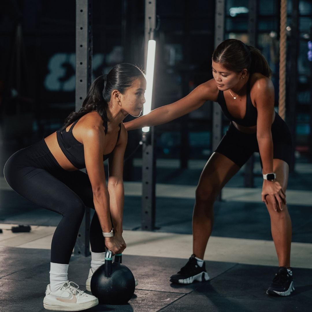 personal trainer instructing a woman lifting weights. 