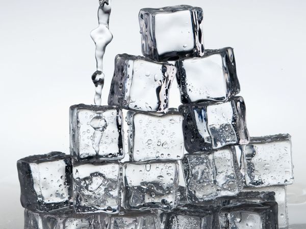 Pyramid of ice cubes with water being poured over the top. 