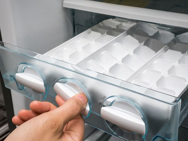 Person twisting a knob on the ice maker in a refrigerator. 