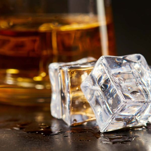 Whiskey with ice cubes next to the glass