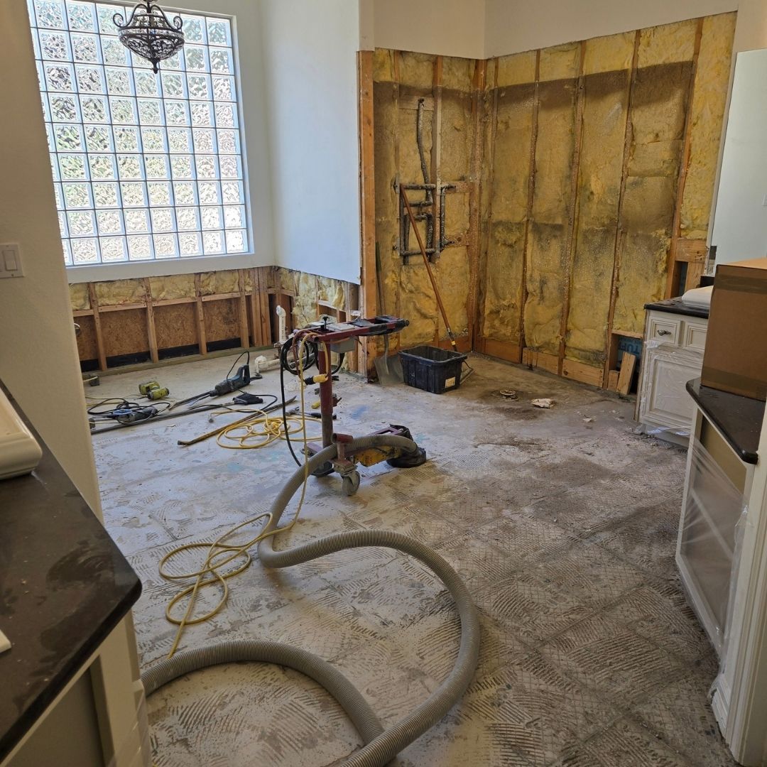 Room undergoing renovation with exposed flooring and wood paneling   