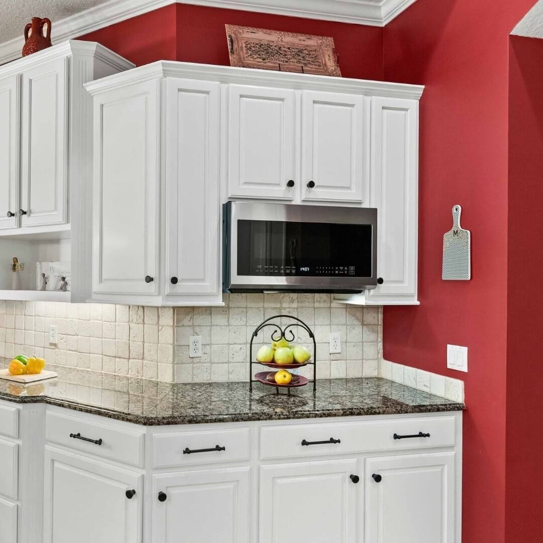 kitchen with white cabinets and red walls