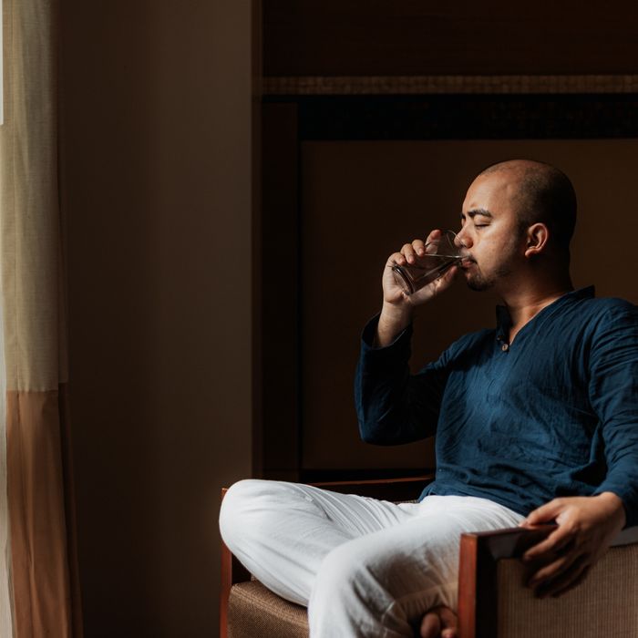 Man in a room drinking water while looking out a window