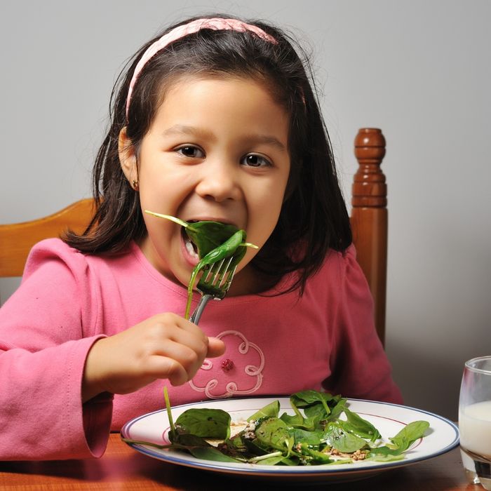 Young girl eating spinach