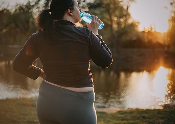 woman drinking water while on a walk