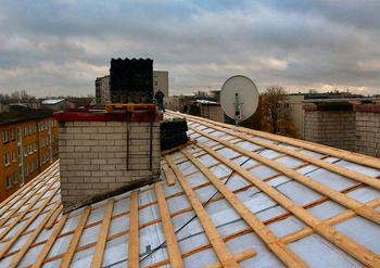 A Northern Virginia home roof being inspected by a contractor during seasonal roof repair, showing shingles and equipment in natural light. Seasonal roof repair in Northern Virginia home after storm damage