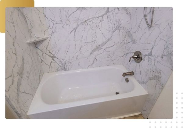 Newly installed white bathtub with marble-look wall surround panels and new chrome fixtures, ready for one-day tub replacement or shower conversion.