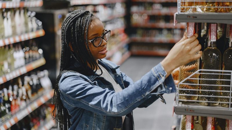 woman picking out liquor bottle at the store