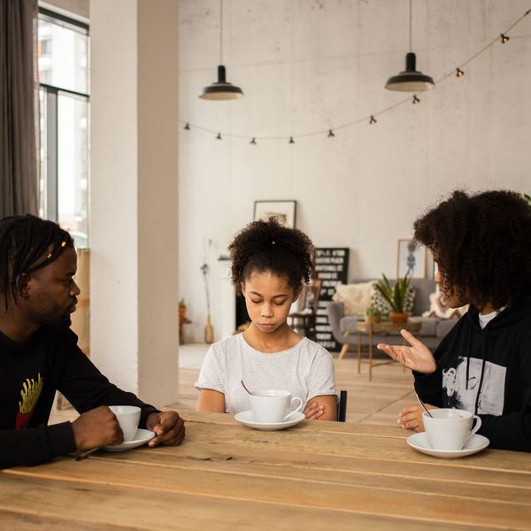 man and woman sitting at table speaking to child at table