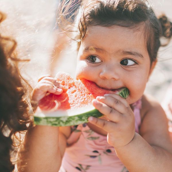 a young child eating watermelon outside