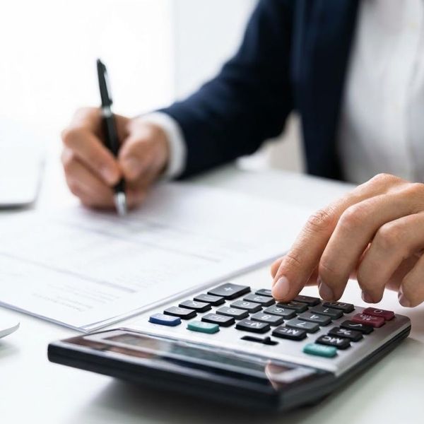 Hands using a calculator and pen over financial documents, representing spousal support calculations.