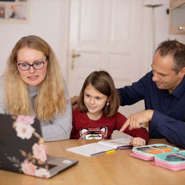 mom and dad sitting at table looking at computer with child