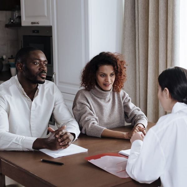 man and woman sitting at table speaking to woman across from them