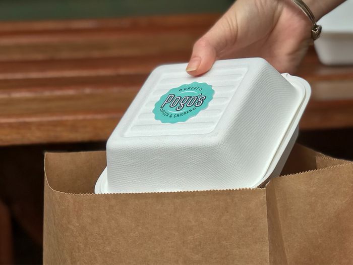 Restaurant placing an eco-friendly takeout container into a paper bag