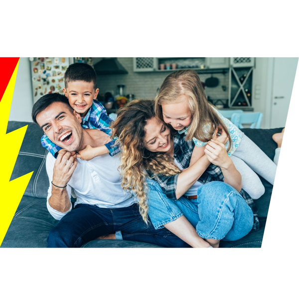 A happy family sitting on a couch smiling with kids hugging the mom and dad