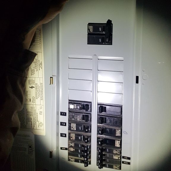 Licensed Electrician Inspecting Electrical Panel at Night