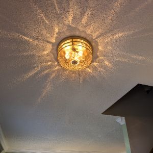 Warm residential lighting fixture illuminating a ceiling with decorative shadows, representing professional electrical services and lighting installation. Residential Electrical Services and Lighting Installation