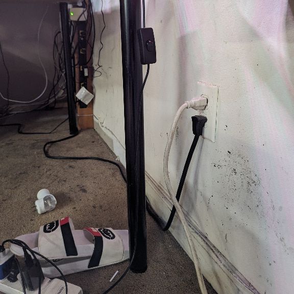 Multiple devices connected to power strips beneath desk
