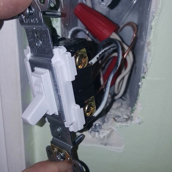 Licensed electrician replacing light switch in Oak Ridge, North Carolina home