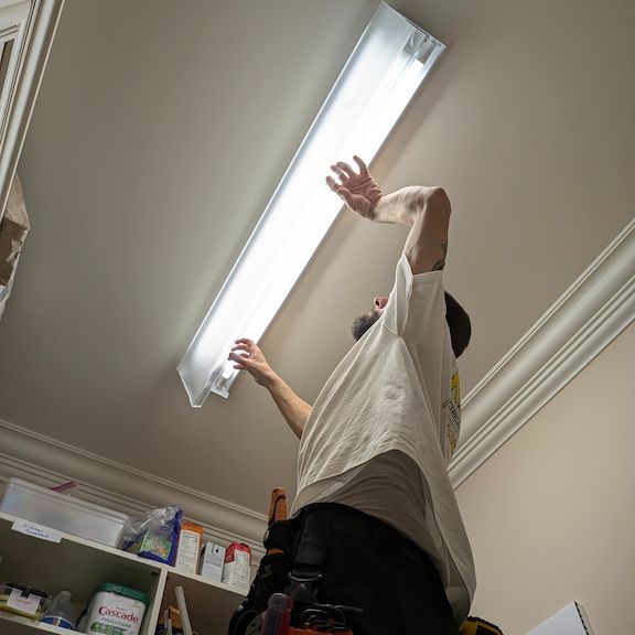 Licensed electrician installing light fixture in Summerfield, North Carolina home