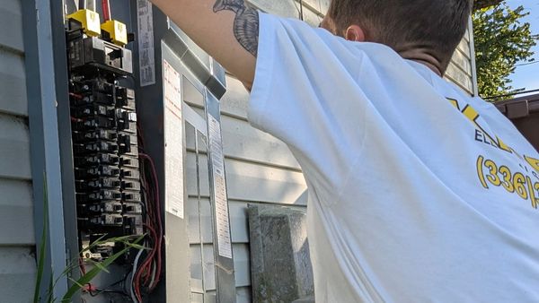 Electrician inspecting a circuit breaker that is tripping and sparking when reset