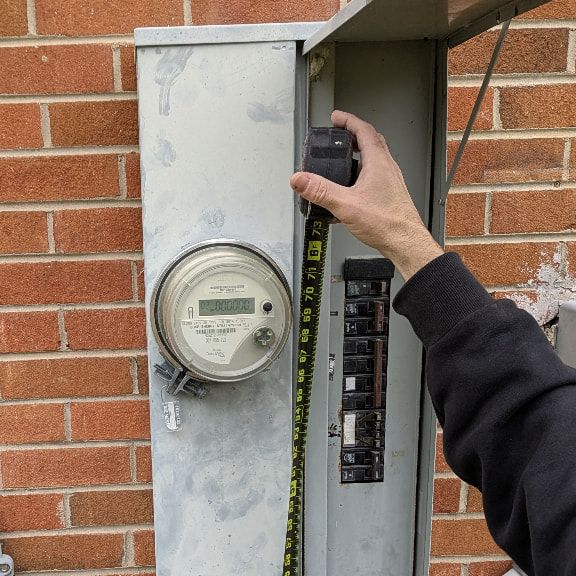 Electrician Measuring Outdoor Electrical Panel for Replacement