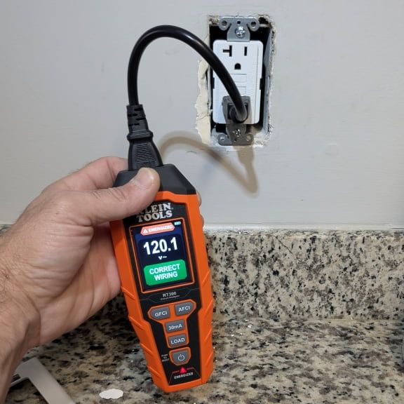 Electrician testing kitchen GFCI outlet showing 120.1 volts in Walkertown NC