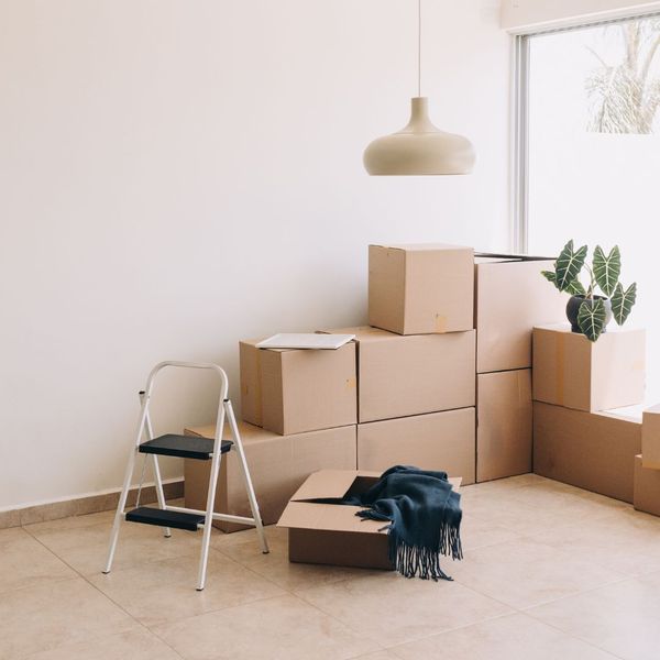 Moving boxes against a white wall and a step ladder