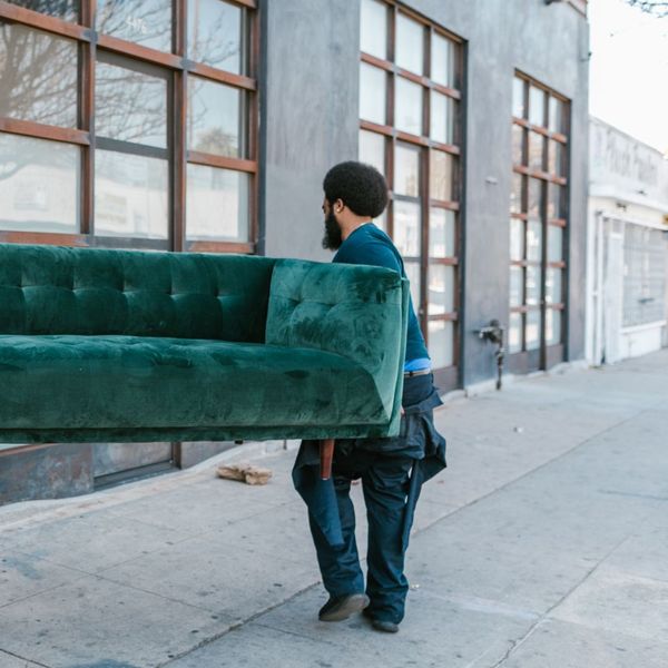 Mover helping carry a green velvet couch