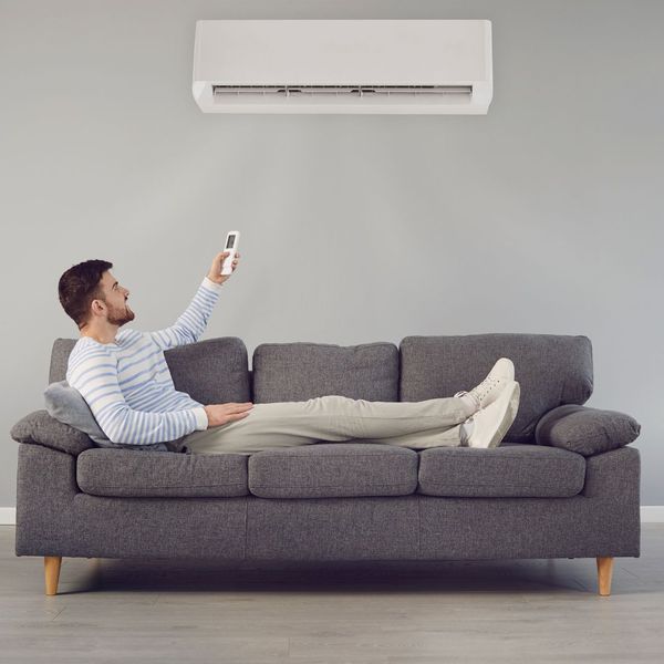Man sitting on couch turning on ac unit How to Choose the Right HVAC System for Your Home1.jpg