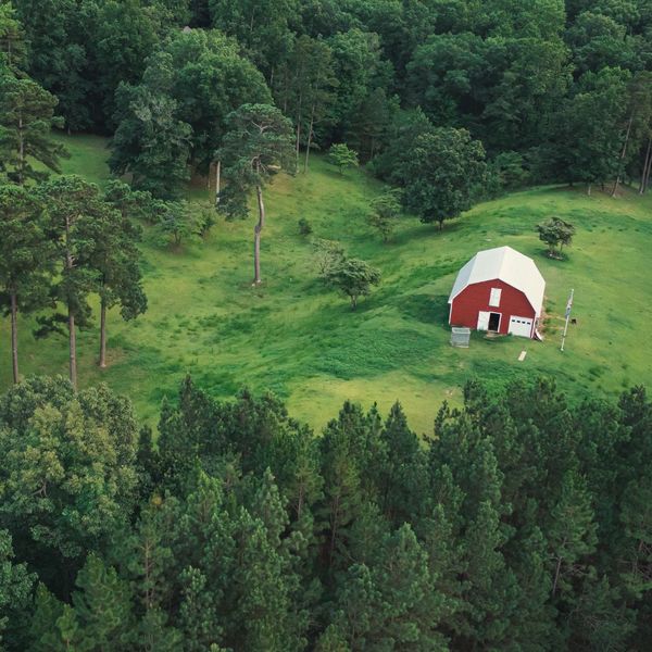 a barn in an open field surrounded by woods