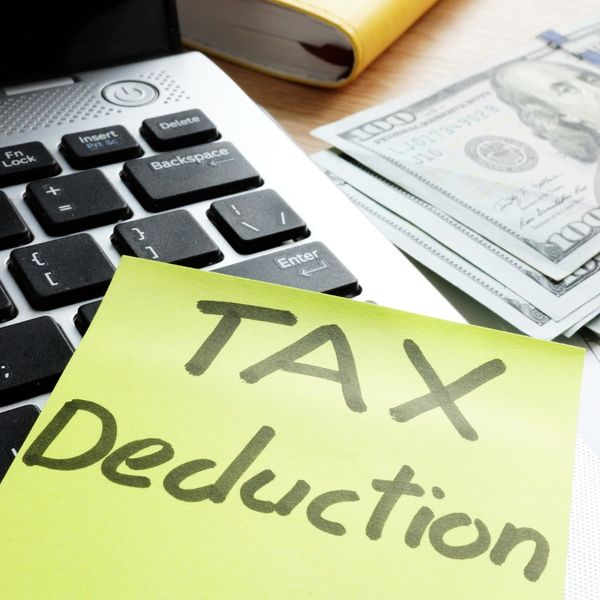 tax deduction sticky note on laptop next to $100 bills