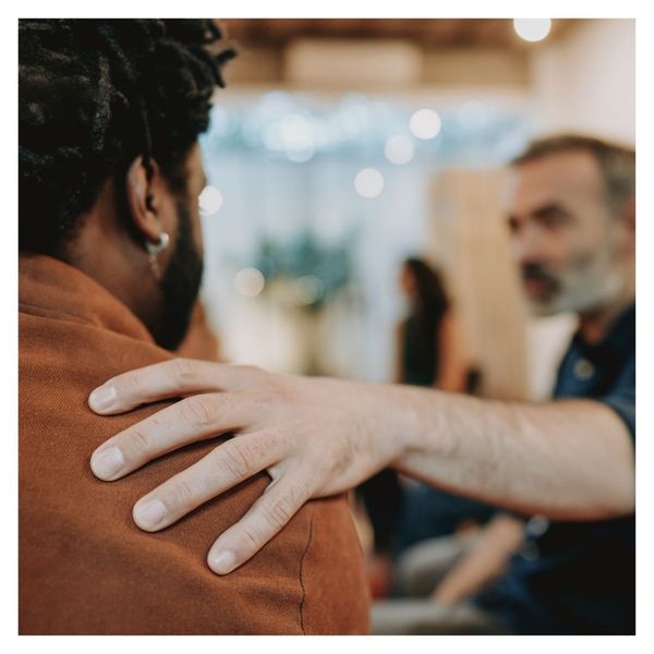 man placing hand on another man's shoulder