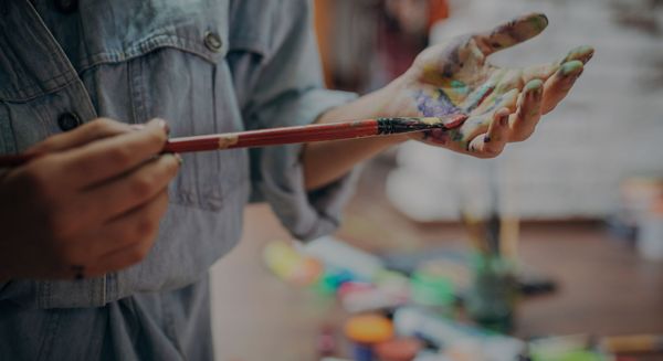 painter holding paintbrush with paint on hands