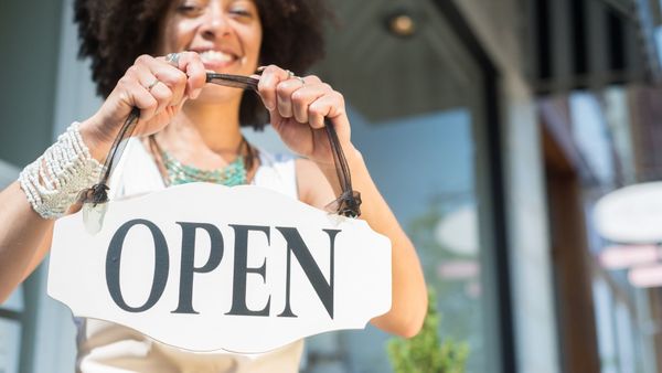 woman holding an open sign 